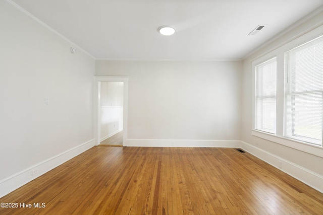 empty room featuring crown molding, baseboards, visible vents, and light wood-style floors