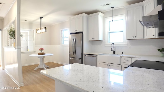 kitchen with a sink, extractor fan, light wood-style flooring, stainless steel appliances, and white cabinetry