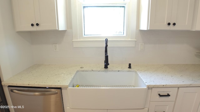 interior space featuring a sink, decorative backsplash, stainless steel dishwasher, and white cabinetry