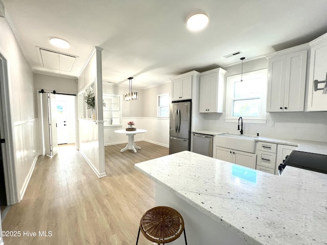kitchen with visible vents, light stone countertops, a sink, light wood finished floors, and appliances with stainless steel finishes