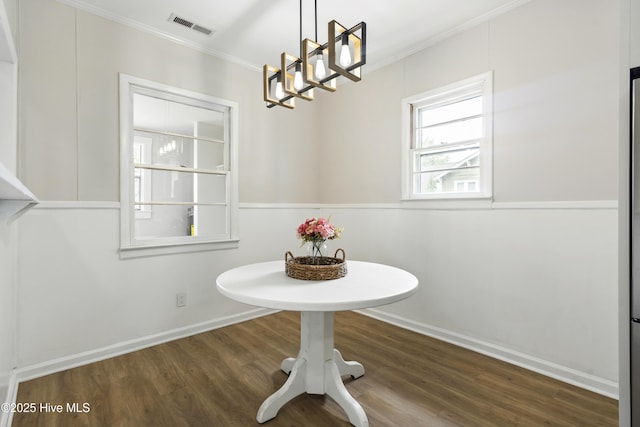 dining space with visible vents, ornamental molding, wood finished floors, and a notable chandelier