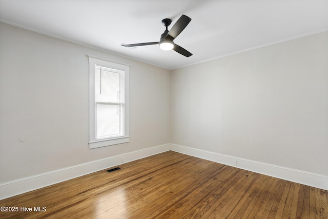 unfurnished room with visible vents, baseboards, crown molding, and hardwood / wood-style floors