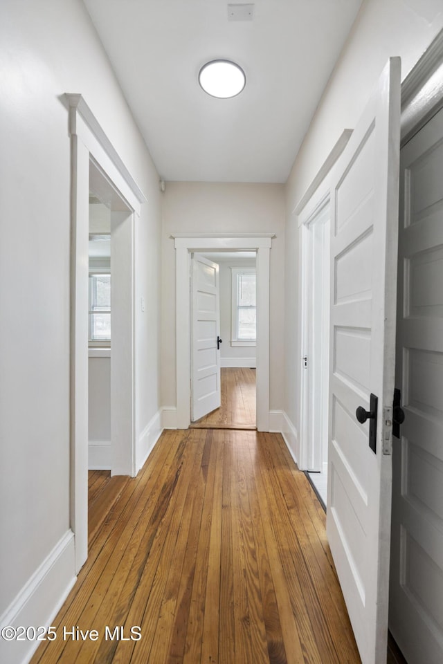 corridor featuring baseboards and hardwood / wood-style floors