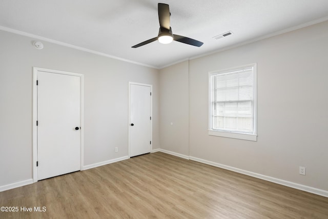 unfurnished bedroom with baseboards, ornamental molding, light wood finished floors, and visible vents