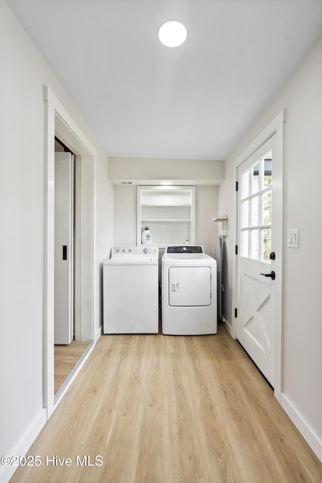 washroom with baseboards, washing machine and dryer, and light wood-style flooring