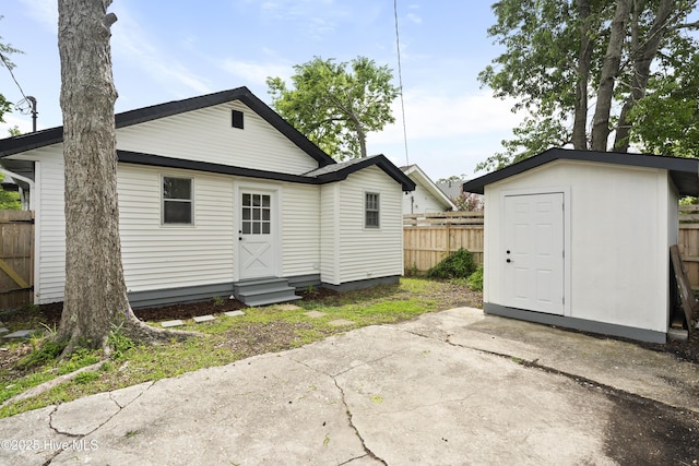 back of property with an outdoor structure, fence, a patio, a shed, and entry steps