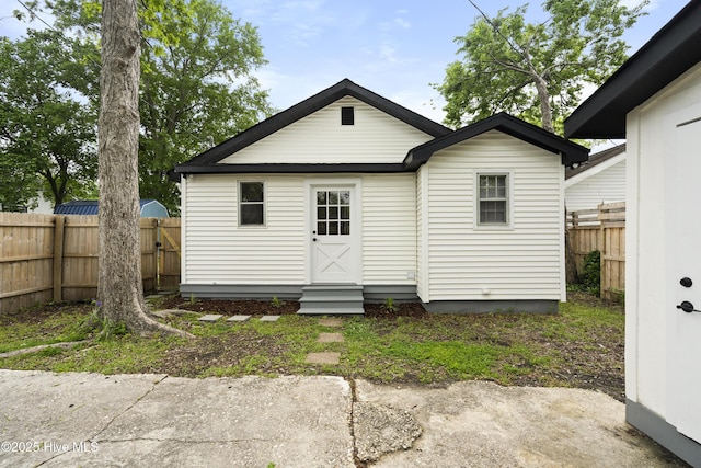 rear view of property featuring fence and entry steps