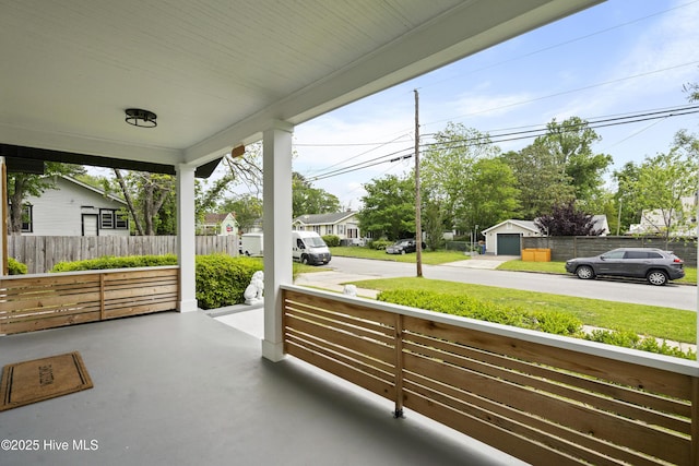 view of patio featuring covered porch, fence, and a residential view
