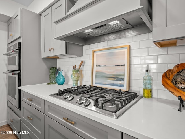 267 Live Oak Rd, Newport, NC 28570 - kitchen with gray cabinets, stainless steel appliances, custom range hood, backsplash, and light countertops
