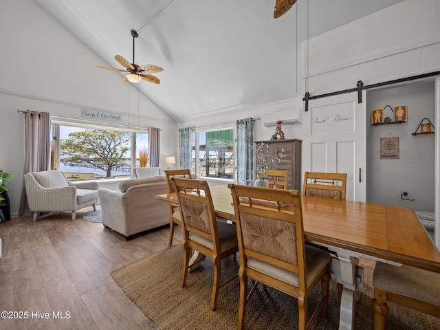 267 Live Oak Rd, Newport, NC 28570 - dining room with a barn door, ceiling fan, high vaulted ceiling, a wall mounted air conditioner, and light wood-style flooring