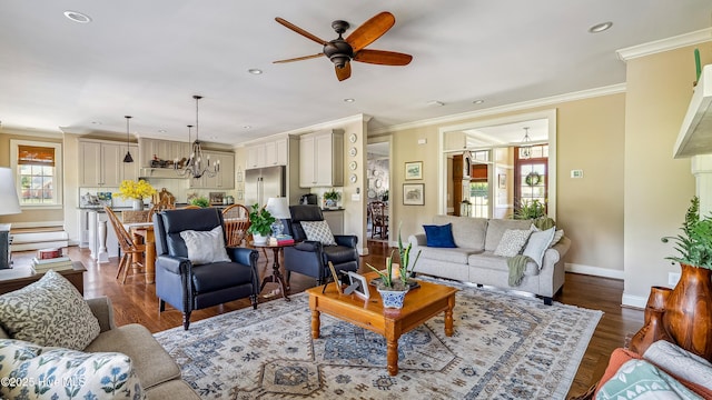 living area with ornamental molding, a ceiling fan, dark wood finished floors, and a healthy amount of sunlight
