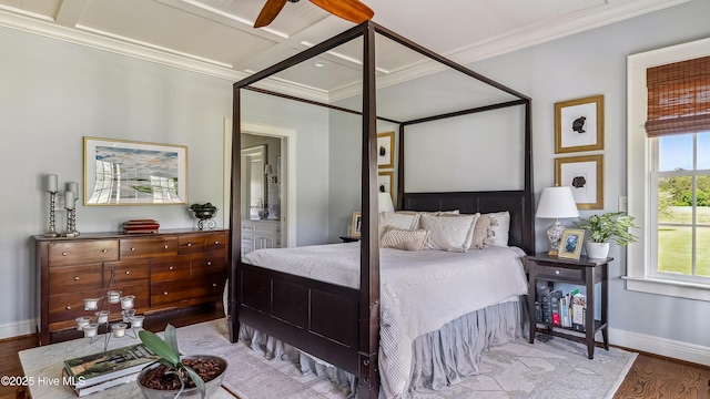 bedroom featuring wood finished floors, crown molding, baseboards, and ensuite bathroom