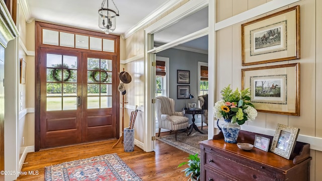 foyer featuring light wood-type flooring, ornamental molding, and french doors