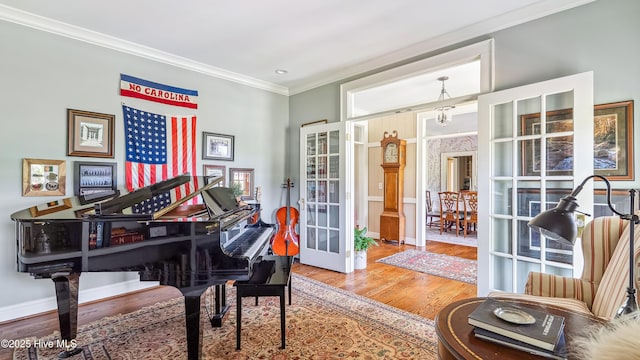 living area featuring wood finished floors, crown molding, baseboards, and french doors