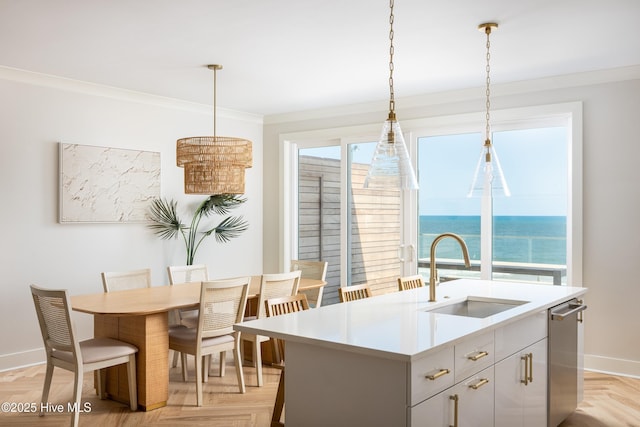 kitchen featuring a sink, baseboards, light countertops, decorative light fixtures, and dishwasher