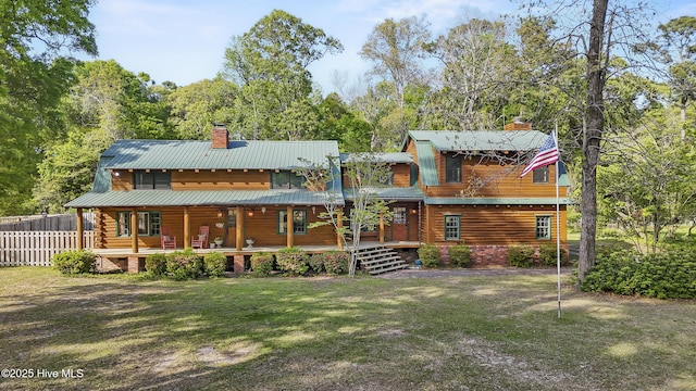 rear view of property with a lawn, a porch, a chimney, and fence