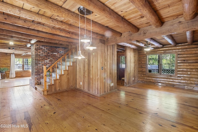 unfurnished living room featuring rustic walls, stairway, beam ceiling, wood ceiling, and hardwood / wood-style flooring
