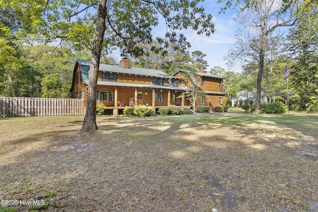 rear view of house with a chimney, fence, and covered porch