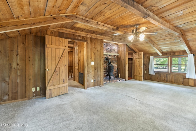 unfurnished living room with lofted ceiling with beams, a ceiling fan, wood walls, wood ceiling, and a wood stove