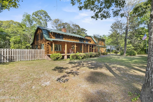 rear view of house with a chimney, fence, log siding, a lawn, and a gambrel roof