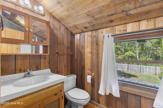 bathroom with toilet, lofted ceiling, wood walls, wooden ceiling, and vanity