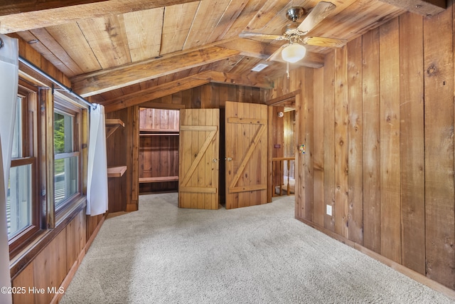 interior space featuring wood walls, a ceiling fan, wooden ceiling, vaulted ceiling with beams, and carpet flooring