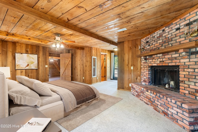 carpeted bedroom with beamed ceiling, wooden walls, a brick fireplace, and wood ceiling