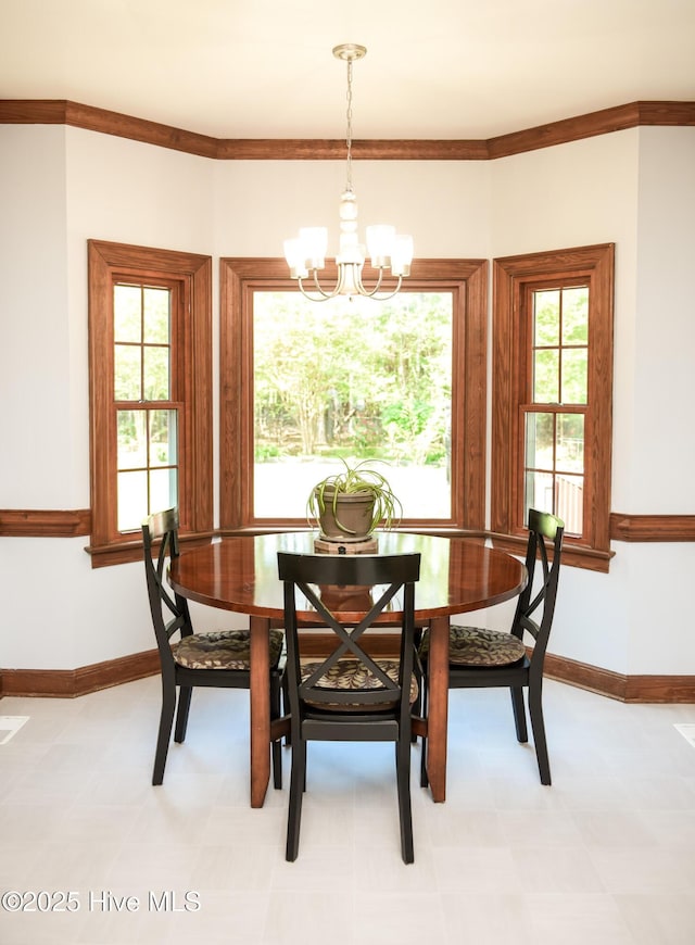dining area featuring a chandelier, crown molding, baseboards, and light floors