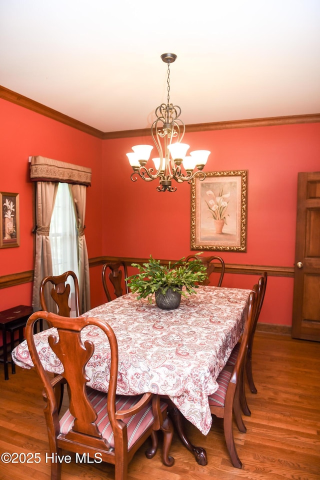 dining space featuring crown molding, baseboards, a notable chandelier, and wood finished floors