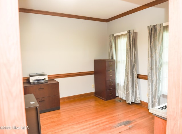 unfurnished office with light wood-type flooring, baseboards, and ornamental molding