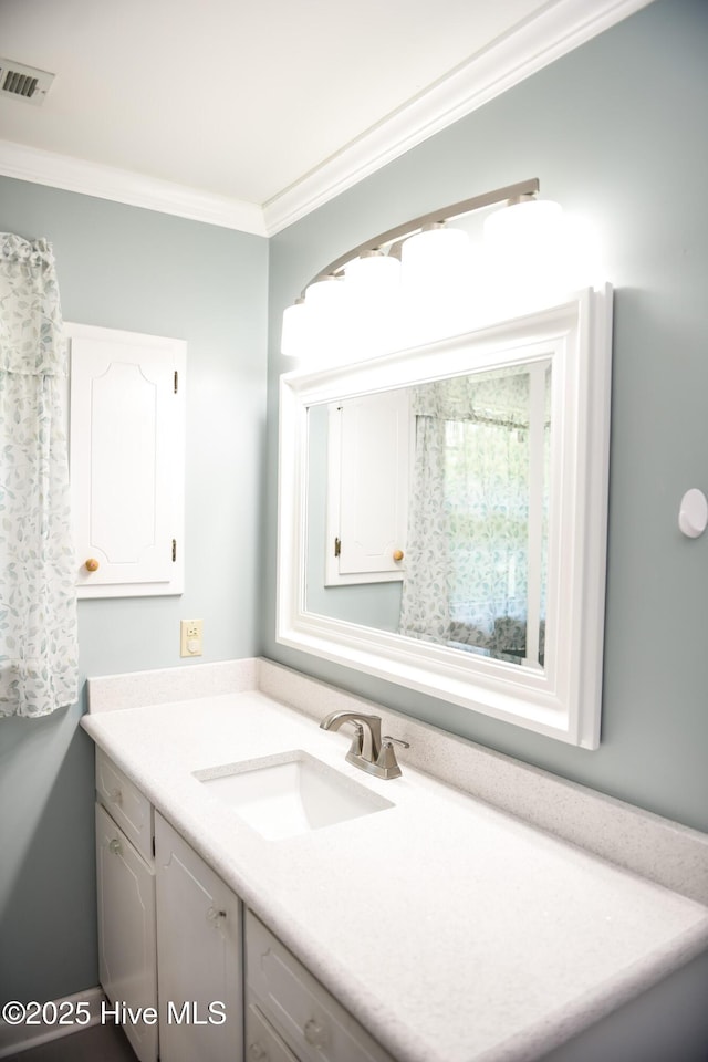 bathroom with ornamental molding, vanity, and visible vents