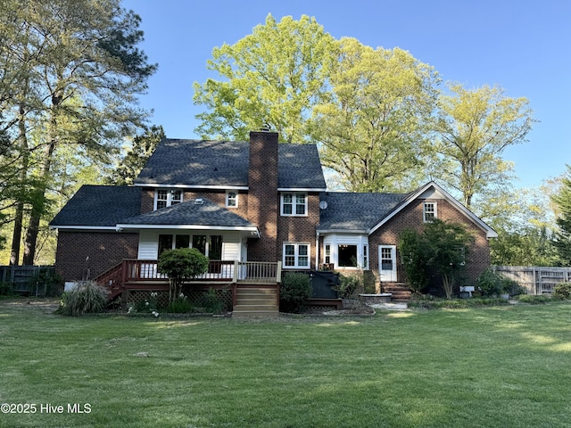 rear view of house with a lawn, fence, and a deck