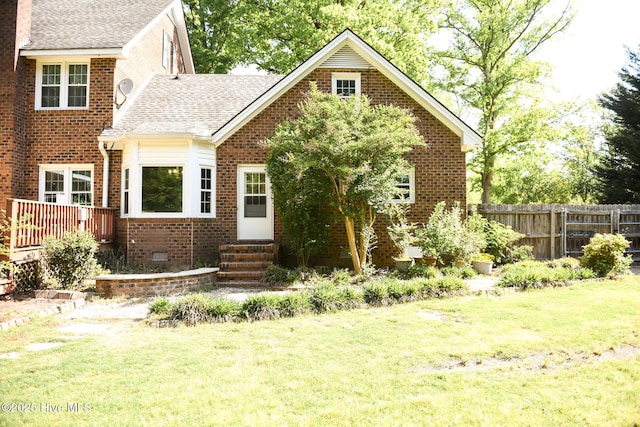view of front of house with brick siding, fence, entry steps, and a front yard