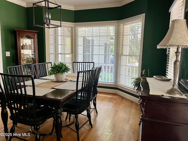 dining area featuring a notable chandelier, a wealth of natural light, ornamental molding, and light wood-style flooring
