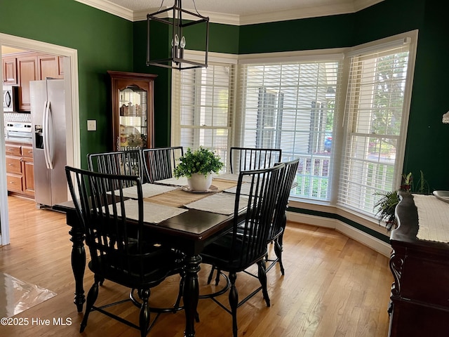 dining room featuring an inviting chandelier, crown molding, light wood finished floors, and baseboards
