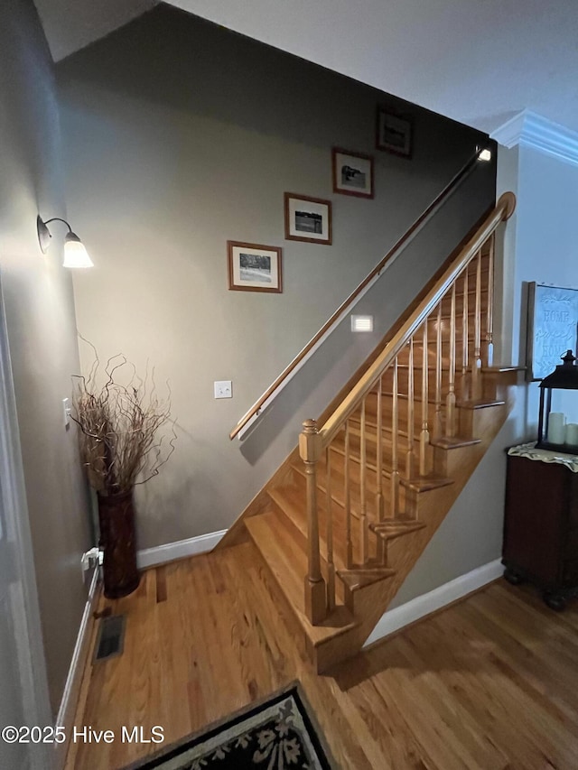 staircase featuring visible vents, baseboards, and wood finished floors