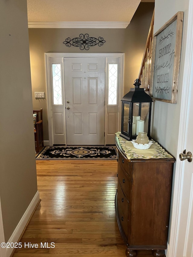 entryway featuring baseboards, wood finished floors, and crown molding