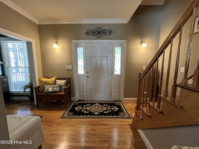 entryway featuring ornamental molding, wood finished floors, and stairway