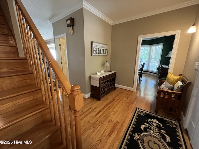 hallway with light wood-type flooring, baseboards, stairway, and ornamental molding