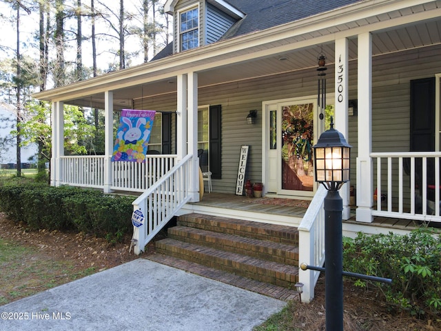 entrance to property with roof with shingles and covered porch
