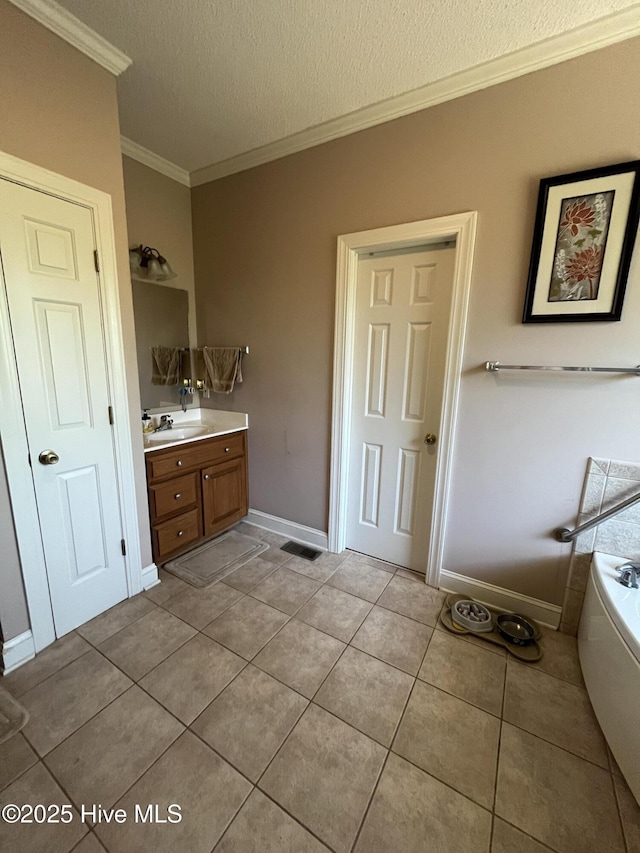 full bath with a textured ceiling, a bath, vanity, ornamental molding, and tile patterned flooring