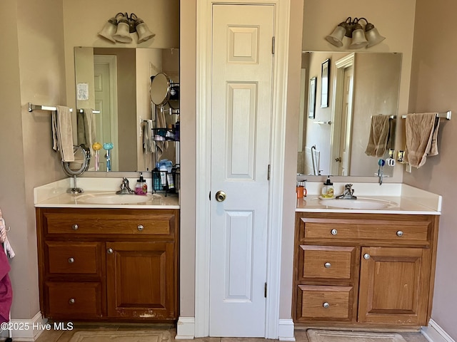 full bathroom featuring two vanities, baseboards, and a sink
