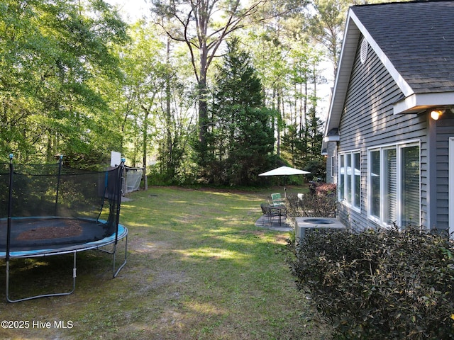 view of yard with a patio, central AC unit, and a trampoline