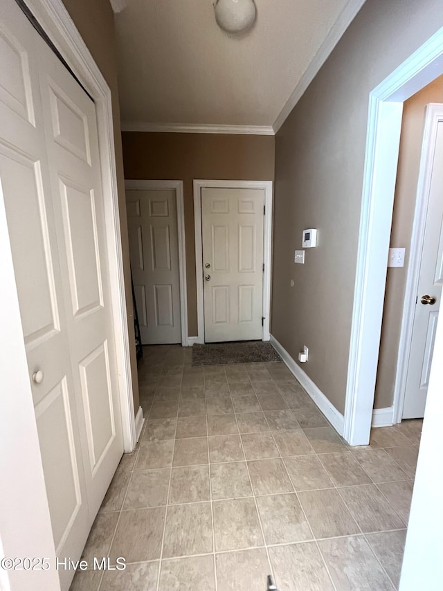 hallway with light tile patterned floors, baseboards, and ornamental molding