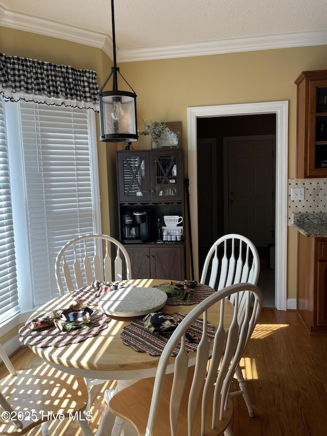 dining room featuring baseboards, wood finished floors, and crown molding