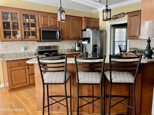 kitchen featuring stainless steel appliances, tasteful backsplash, glass insert cabinets, a breakfast bar, and decorative light fixtures