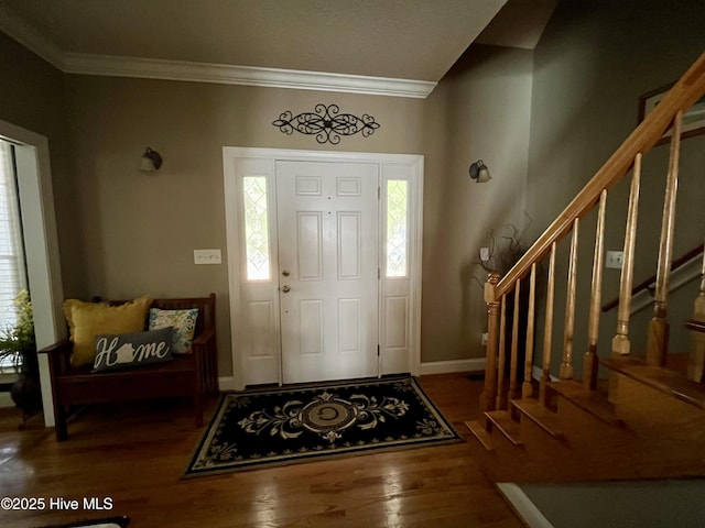 foyer with baseboards, ornamental molding, wood finished floors, and stairs