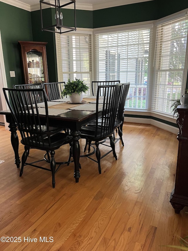 dining space with light wood-style floors, a notable chandelier, and crown molding