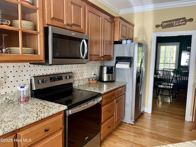 kitchen with brown cabinets, backsplash, ornamental molding, and stainless steel appliances