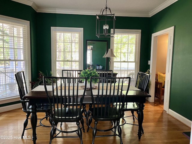 dining area featuring wood finished floors, baseboards, ornamental molding, and an inviting chandelier